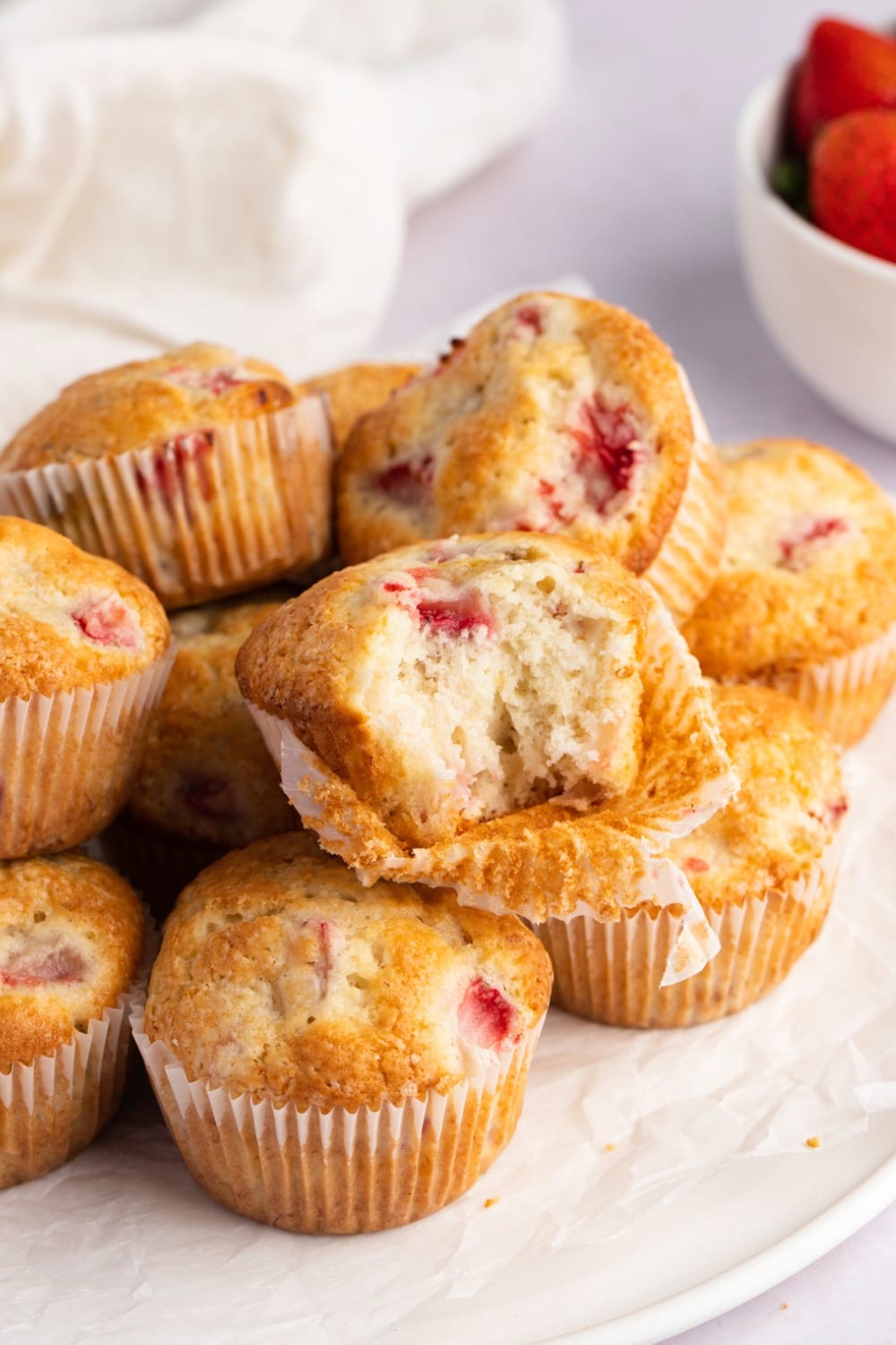 Muffins with strawberry bits stack on plate. 